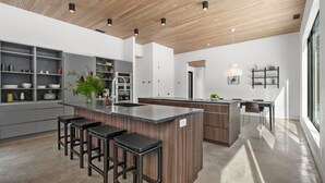 Een moderne keuken met een centraal eiland, barstoelen en inbouwplanken.