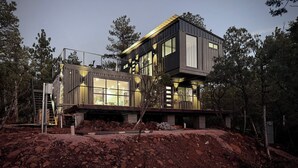 Una casa moderna de dos pisos amb grans finestres, un balcó i un solar en primer pla.