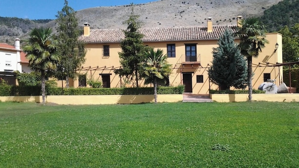 Un edificio amarillo con tejado de baldosas, rodeado de un césped cuidado y palmeras.