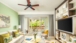 Ein Wohnzimmer mit Sofa, Couchtisch, Fernseher und einem Balkon mit Gartenmöbeln.