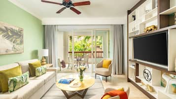 Una sala de estar con sofá, mesa de centro, televisor y un balcón con mobiliario exterior.