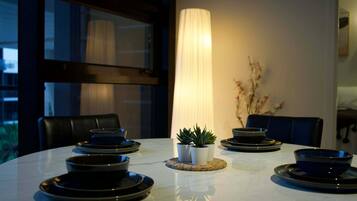 A dining table with black plates and bowls, a tall white lamp, and two potted plants.