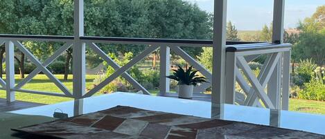 A covered outdoor area with a stone-tiled floor, white railings, and a potted plant.