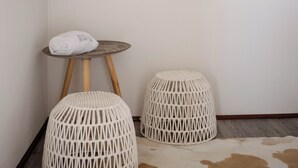 A room with a wooden sign on the wall, a small round table with a rolled towel, two wicker stools, and a cowhide rug. - Drovers Run B&B and Events Venue (Marrar)