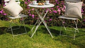 A garden with a table and chairs, surrounded by colorful flowers and a building in the background. - Drovers Run B&B and Events Venue (Marrar)