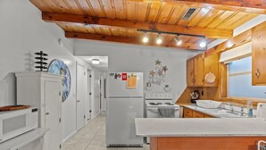 A kitchen with white cabinets, a wooden ceiling, a refrigerator, a stove, and a sink. - Pool! Blocks away from beach. Dog-Friendly! (Oak Island)