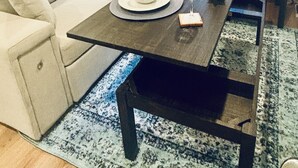 En moderne stue med et mørkt træsofabord, en hvid sofa og en blå måtte.