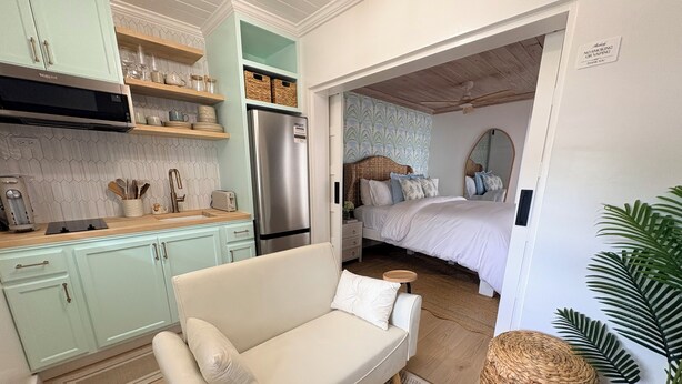 A modern kitchen with light green cabinets, a stainless steel refrigerator, and a wooden countertop.