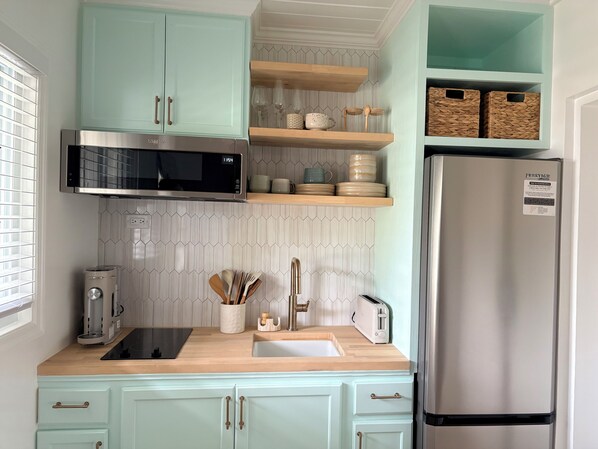 A kitchen with a microwave, toaster, sink, and a refrigerator.
