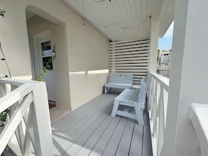 Une véranda avec des balustrades blanches, un banc et une petite table.