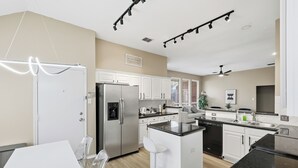 A modern kitchen with white cabinets, stainless steel appliances, and a central island. - Modern 4B Retreat with Pool in Frisco (Frisco)
