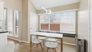 A modern kitchen with a white table, two chairs, and a stainless steel trash can. - Modern 4B Retreat with Pool in Frisco (Frisco)