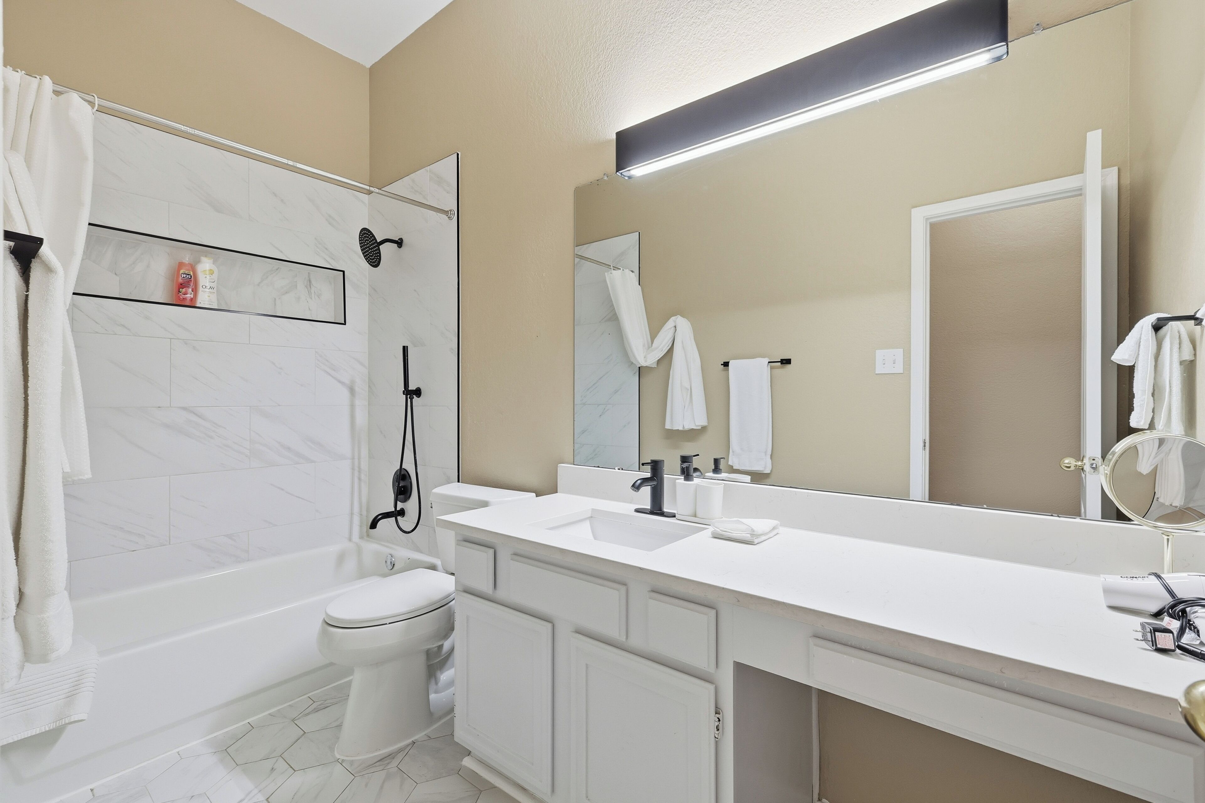 Un bagno moderno con vasca, servizi igienici e un mobile lavabo con specchio.