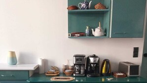 Una cocina con armarios color turquesa, una cafetera, un tostador y diversos utensilios de cocina sobre la encimera.