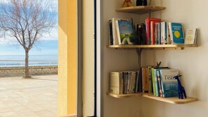Una habitación con un ventanal grande, una estantería y una pequeña mesa.