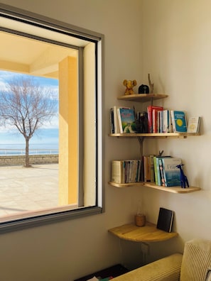 Ein Zimmer mit einem großen Fenster, einem Bücherregal und einem kleinen Tisch.