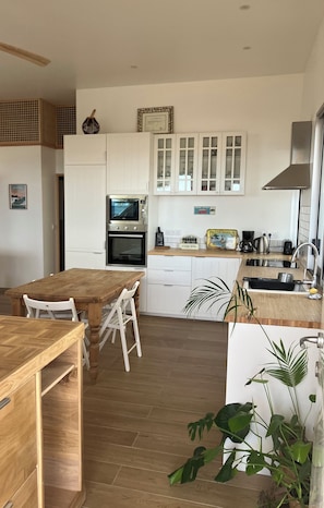 Eine kleine Küche mit weißen Schränken, einem Holztisch und einem eingebauten Backofen.
