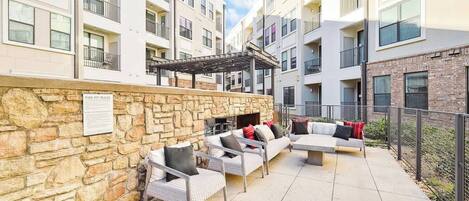 A courtyard with outdoor seating, stone walls, and a fire pit area.
