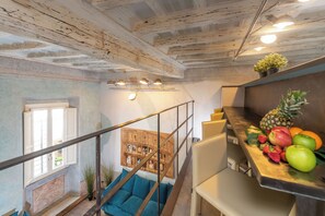 Eine moderne Küche mit Holzbalkendecke, einer Treppe mit blauen Kissen und einer Obstauslage.