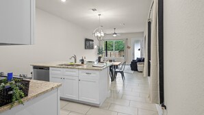A modern kitchen with white cabinets, a granite countertop, and a built-in dishwasher. - Modern 3BR Near RiverWalk•Sleeps 8•Free Parking (San Antonio)