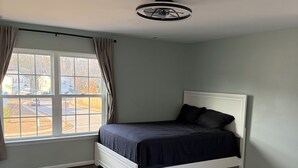 Une chambre à coucher avec un lit, une fenêtre et un ventilateur de plafond.