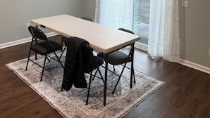 Un coin repas comprenant une table et des chaises, un tapis à motifs et une fenêtre ornée de rideaux légers.