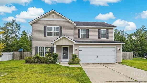 Une maison à deux étages avec un garage, un porche à l’avant et une pelouse bien entretenue.