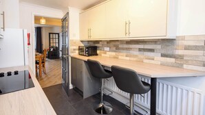 A modern kitchen with a black stove, white cabinets, and a tiled backsplash. - Ty Glyndwr by STAE-Homes (Trehafod)