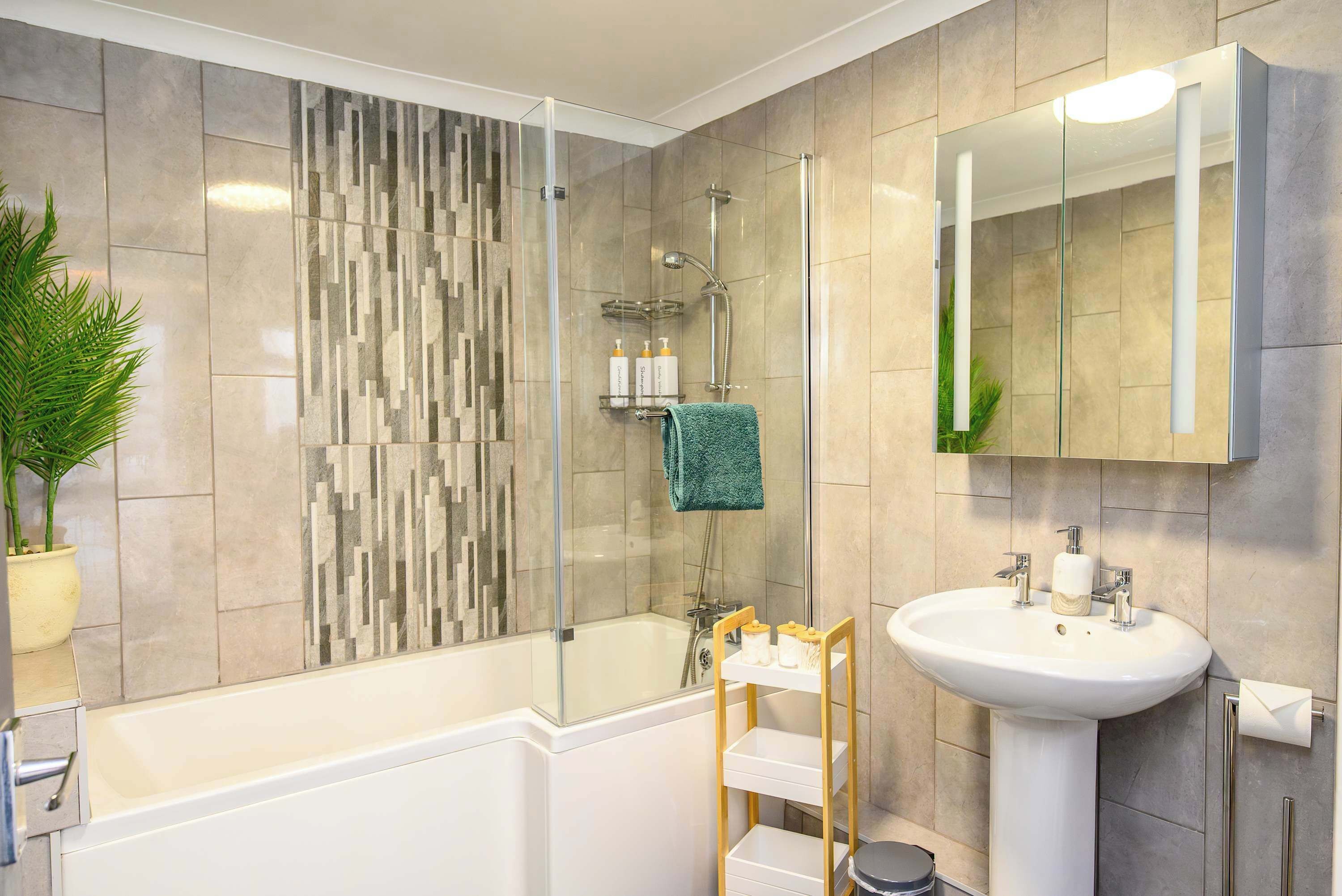 A modern bathroom with a glass-enclosed shower, a white sink, and a mirror above it.