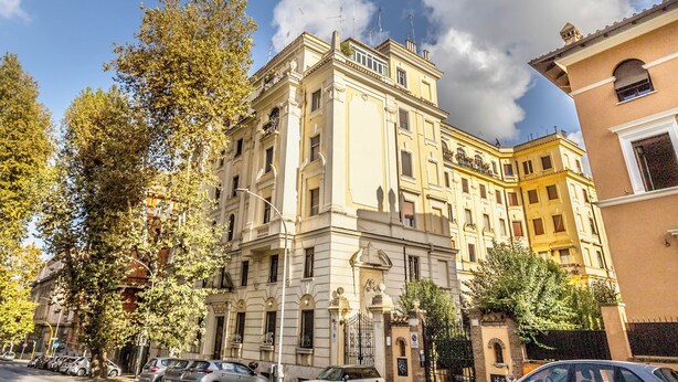 A multi-story building with classical architecture, featuring a central entrance with a decorative archway, large windows, and a balcony on the upper floors. - Bright & Stylish 2 bed Apartment in Trastevere (Roma)