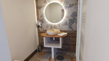 A bathroom with a round mirror, a wooden vanity, and a patterned floor.