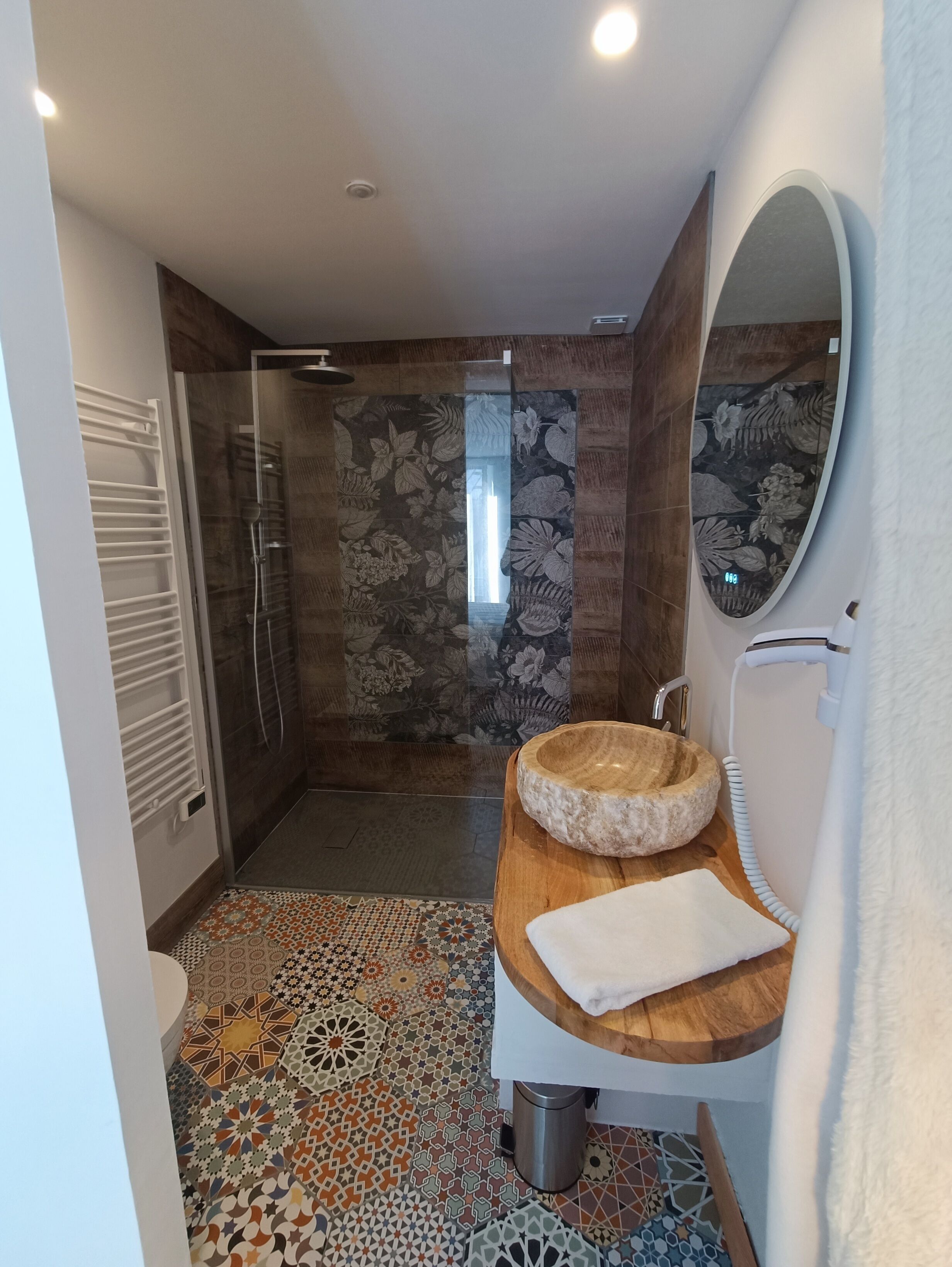 Un baño moderno con ducha, tocador de madera con lavabo y un espejo grande.