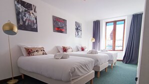 Een hotelkamer met twee bedden, een vloerlamp en kunstwerken aan de wanden.