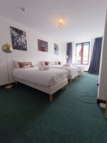 A hotel room with two beds, a floor lamp, and artwork on the walls.
