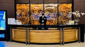 Ein Hotelrezeptionsschalter mit modernem Design, einem digitalen Bildschirm und einer Wandverkleidung.