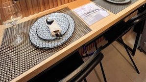 Ein Essbereich mit einem großen Flachbildfernseher, einem Holztisch, zwei gedeckten Plätzen und einer Speisekarte.