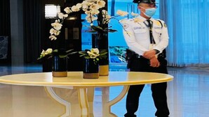 Eine Hotelhalle mit einem runden Tisch, Blumenvasen und einer Person in Uniform.