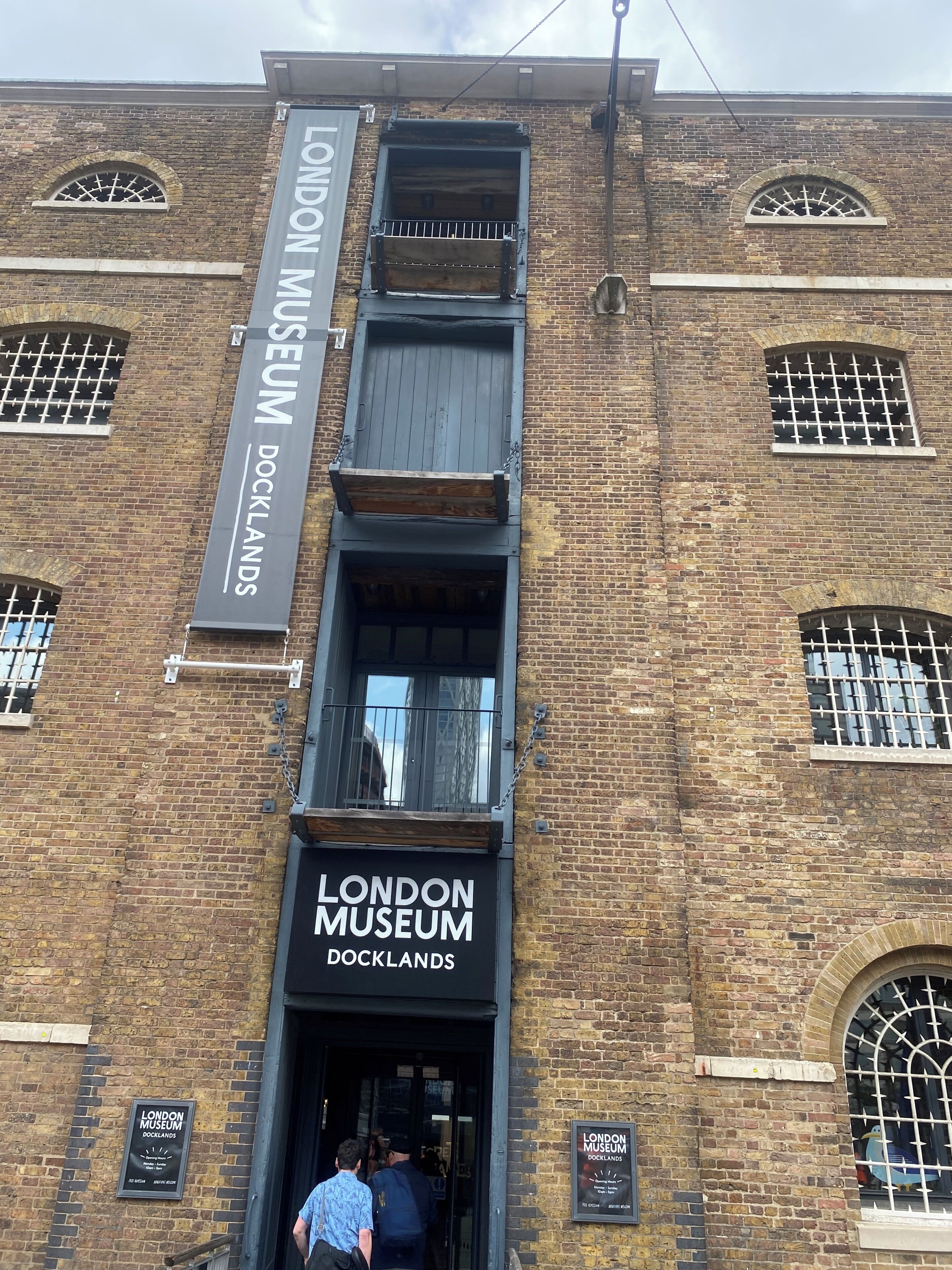 Tiilestä rakennettu rakennus, jossa on kyltti, jossa lukee »LONDON MUSEUM DOCKLANDS», ja suuri sisäänkäynti.