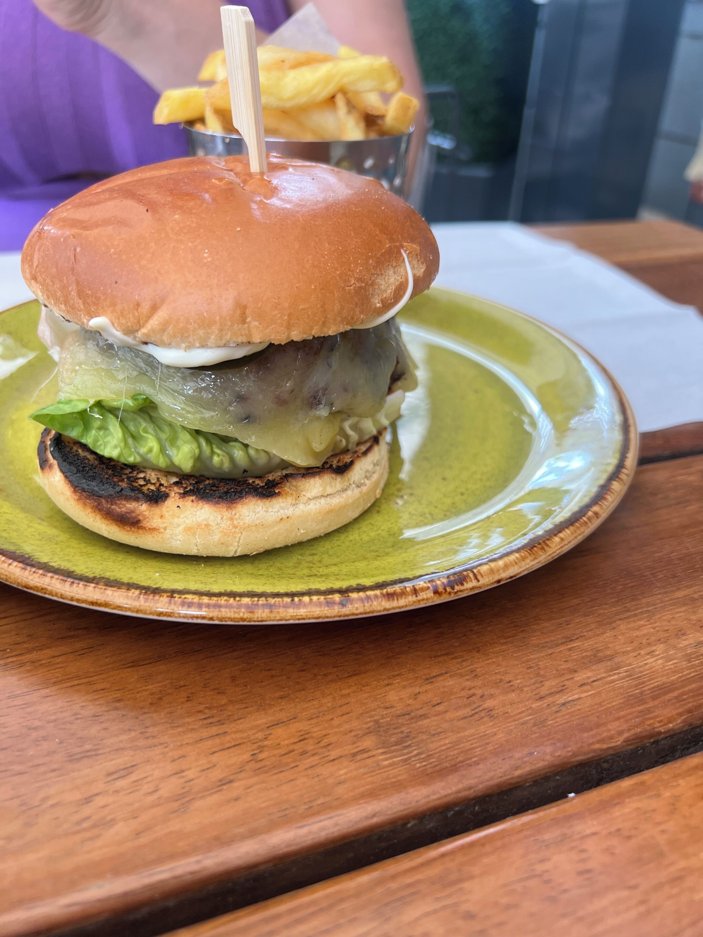 Un entrepà sobre un plat verd amb taula de fusta.