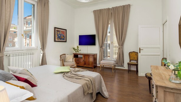 Une chambre bien éclairée, avec un lit, une télévision et un bureau avec une chaise.