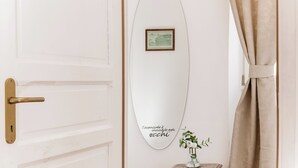 Une porte blanche avec une poignée dorée, un tableau encadré et un miroir en forme de planche de surf portant un texte en italien.