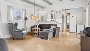 Amplia sala de estar con un sofá gris, un sillón a juego, una mesa de centro de madera y una lámpara de pie.