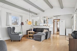 A spacious living area with a grey sofa, a matching armchair, a wooden coffee table, and a floor lamp. - Lovely holiday home near water and nature (Hadsund)