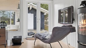 Una sala de estar moderna con chimenea, televisor y puerta corrediza de vidrio que da a un espacio exterior.