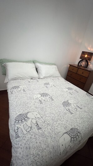 Quarto com cama, almofadas, penteadeira e luminária.