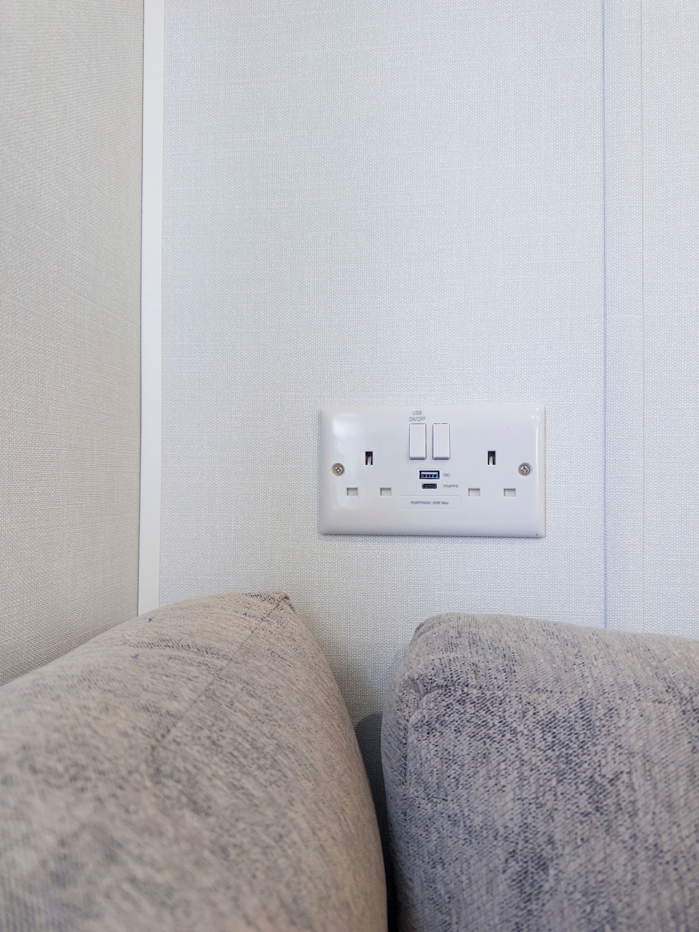 A power outlet with USB and PD ports, a socket, and a switch on a textured wall.