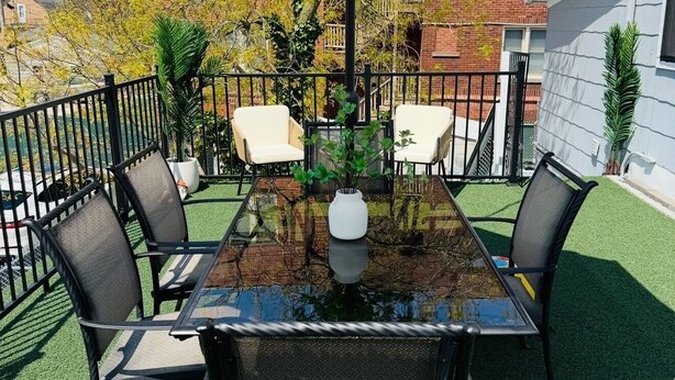A patio with a glass-top table, four chairs, a striped umbrella, and a potted plant. - Poseidon's Corner #2 of 3 units on this property (Sandusky)