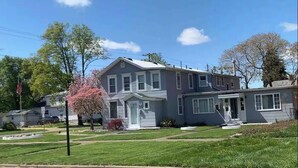 A two-story residential house with a front porch, a garage, and a well-maintained lawn. - Poseidon's Corner #2 of 3 units on this property (Sandusky)