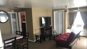 A living room with a dining table, chairs, a sofa, a TV, and a fireplace. - Poseidon's Corner #2 of 3 units on this property (Sandusky)