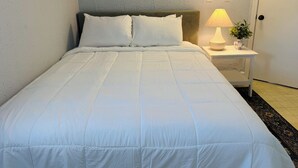 A neatly made bed with white bedding, a bedside lamp, and a small plant on a bedside table. - Poseidon's Corner #2 of 3 units on this property (Sandusky)